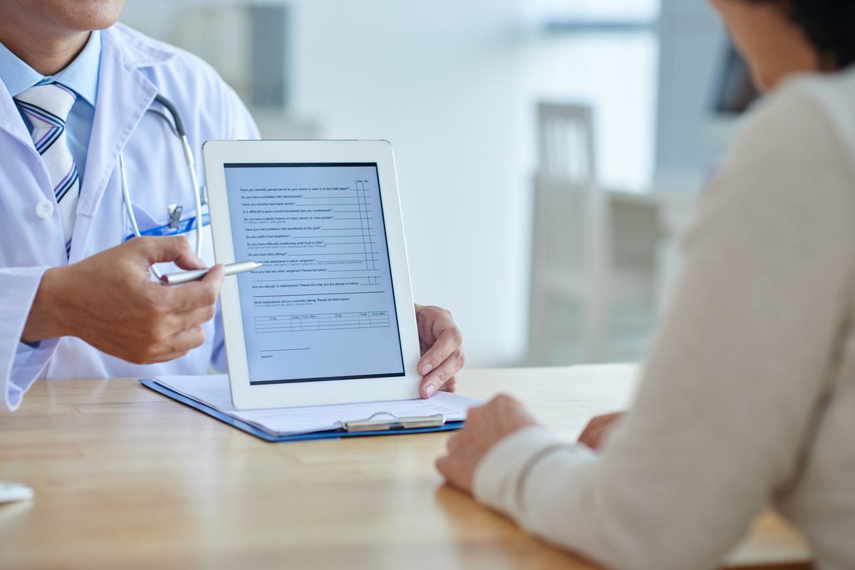 Médico mostrando tablet con formulario a paciente